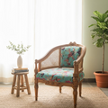 A vintage-style wooden armchair with woven cane backrest and turquoise floral upholstered seat and back cushion, placed on a jute rug in a bright room with sheer curtains, a small wooden stool, and a potted plant.