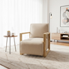 A modern beige armchair with a light wood frame sits on a textured light gray rug in a bright, contemporary living room.