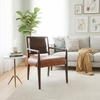 A mid-century modern accent chair with brown leather upholstery and dark wood arms and legs, positioned on a light beige patterned area rug in a bright, contemporary living room.