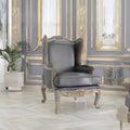 A luxury interior room featuring two gray wingback armchairs with ornate gold-trimmed wooden frames, set against a wall with decorative gold paneling and mirrors. The room has light-colored herringbone wood flooring and a matching marble-top table in the foreground.
