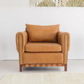 A wall tapestry featuring a modern floral pattern with two prominent red-orange poppy-like flowers and beige leaf silhouettes, hanging on a white wall above a tan leather armchair in a styled living room.