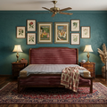 A styled bedroom interior with a dark reddish-brown wooden bed centered against teal walls, surrounded by framed botanical prints, matching lamps, a patterned rug, curtains, and a chair by the window.